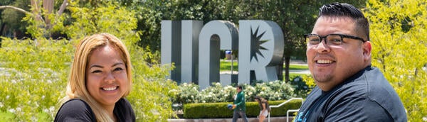 UCR student veterans smile in front of large metal letters spelling out UCR